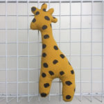 Giraffe accessoire voor baby met piepertje in het okergeel met zwarte dots