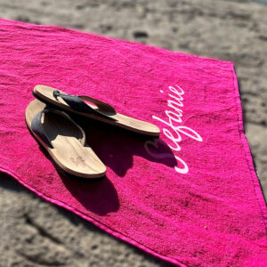 Fuchsia roze strandlaken met naam in het wit op het strand
